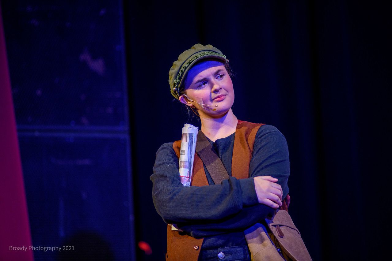 A woman is standing on a stage holding a piece of paper.