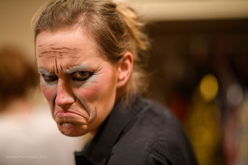 A woman with makeup on her face is making a funny face.