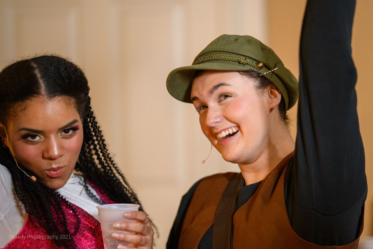 Two women are standing next to each other and one is holding a cup.