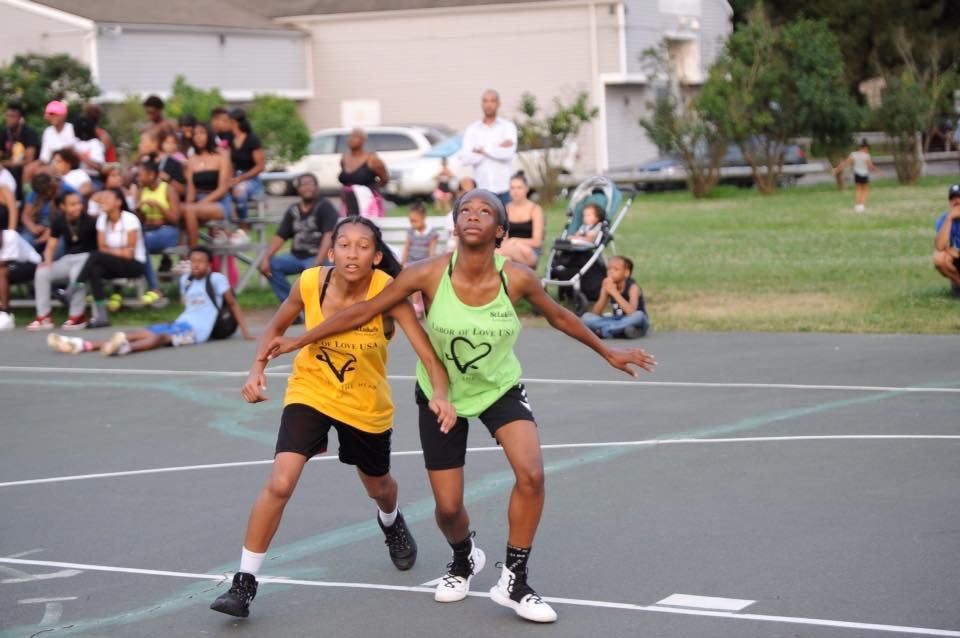 Two girls are playing basketball on a court with a crowd watching