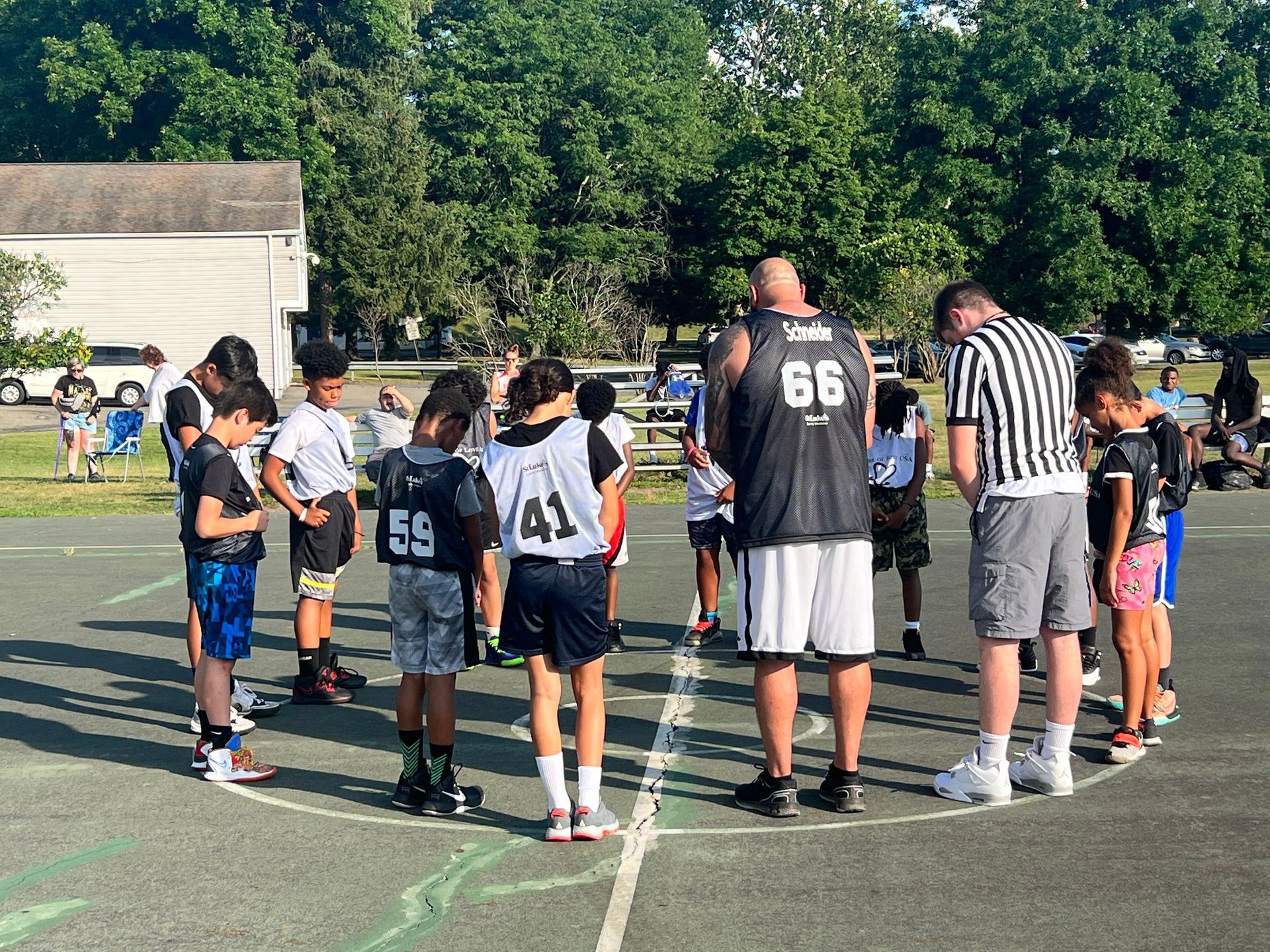 A group of children are standing in a circle on a basketball court.