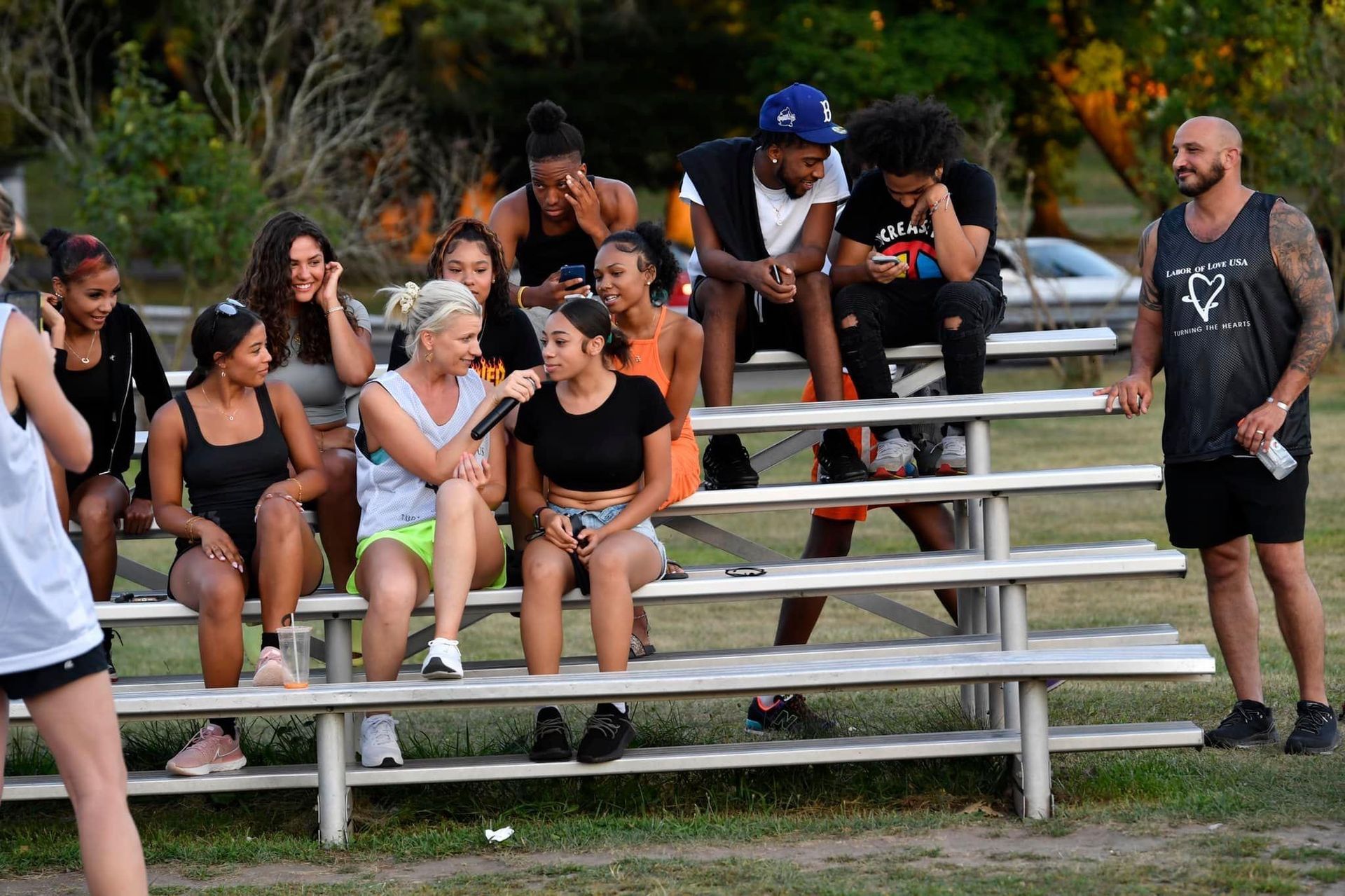 A group of people are sitting on bleachers talking to each other.