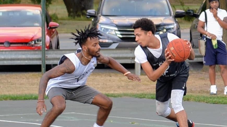 Two young men are playing basketball on a court.