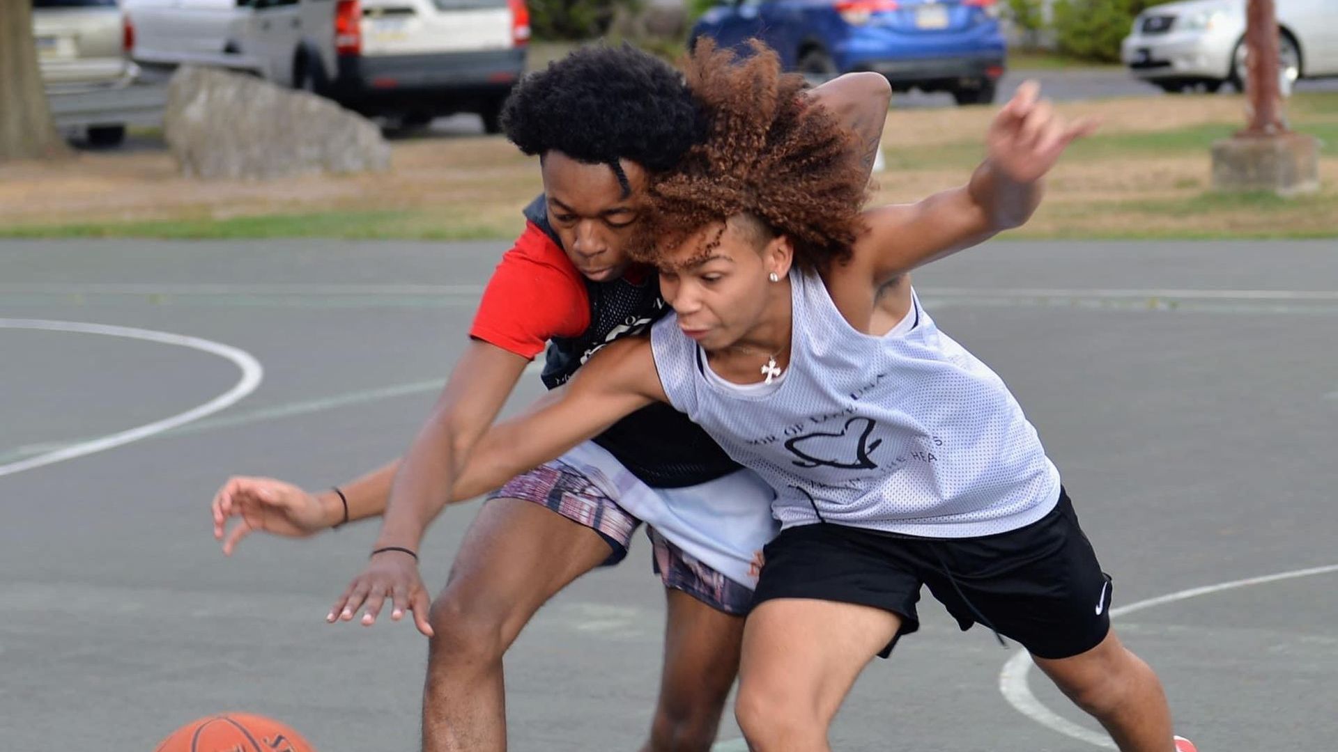 A man and a woman are playing basketball on a court.