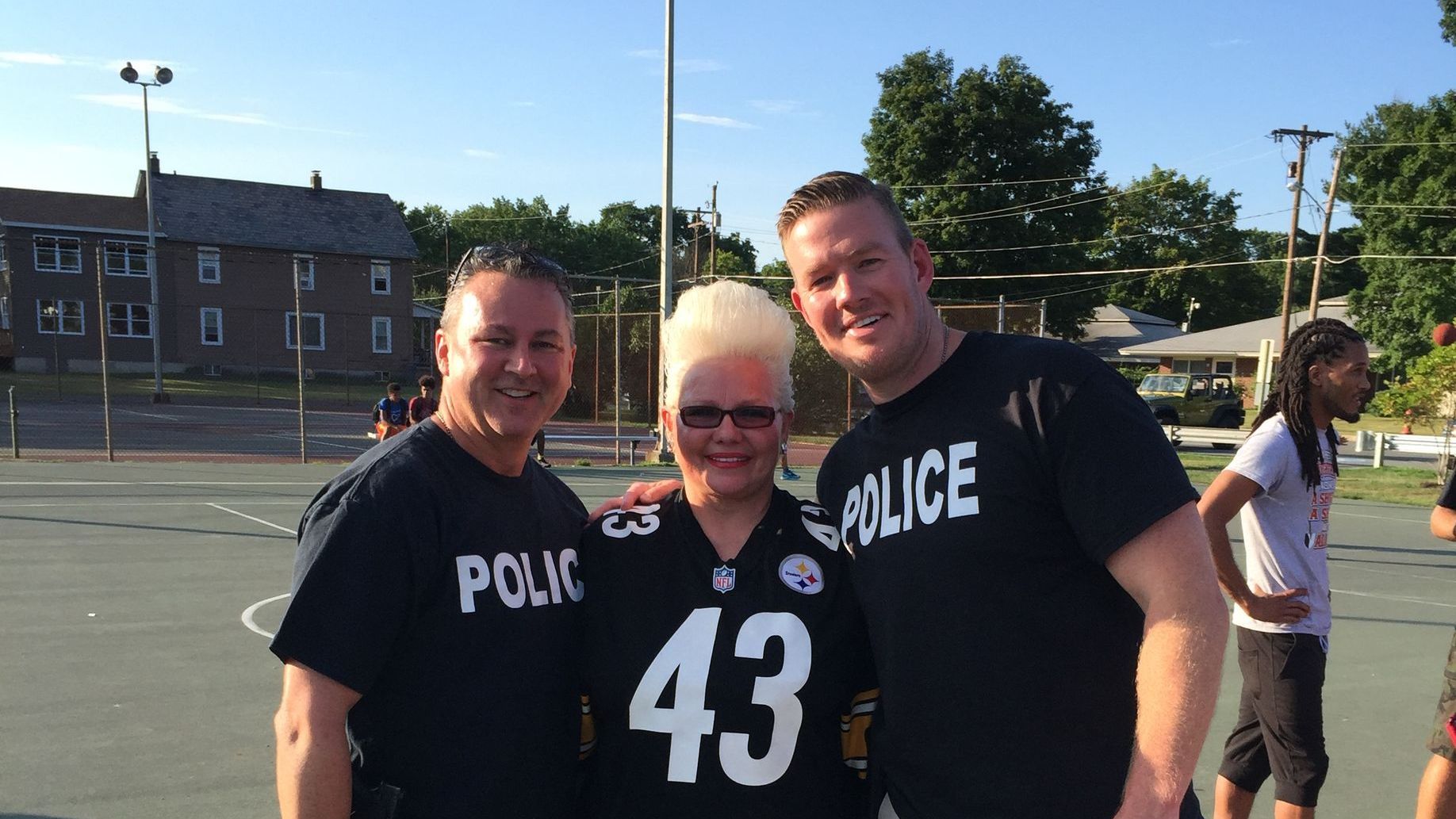 Two men and a woman are posing for a picture while wearing police shirts.