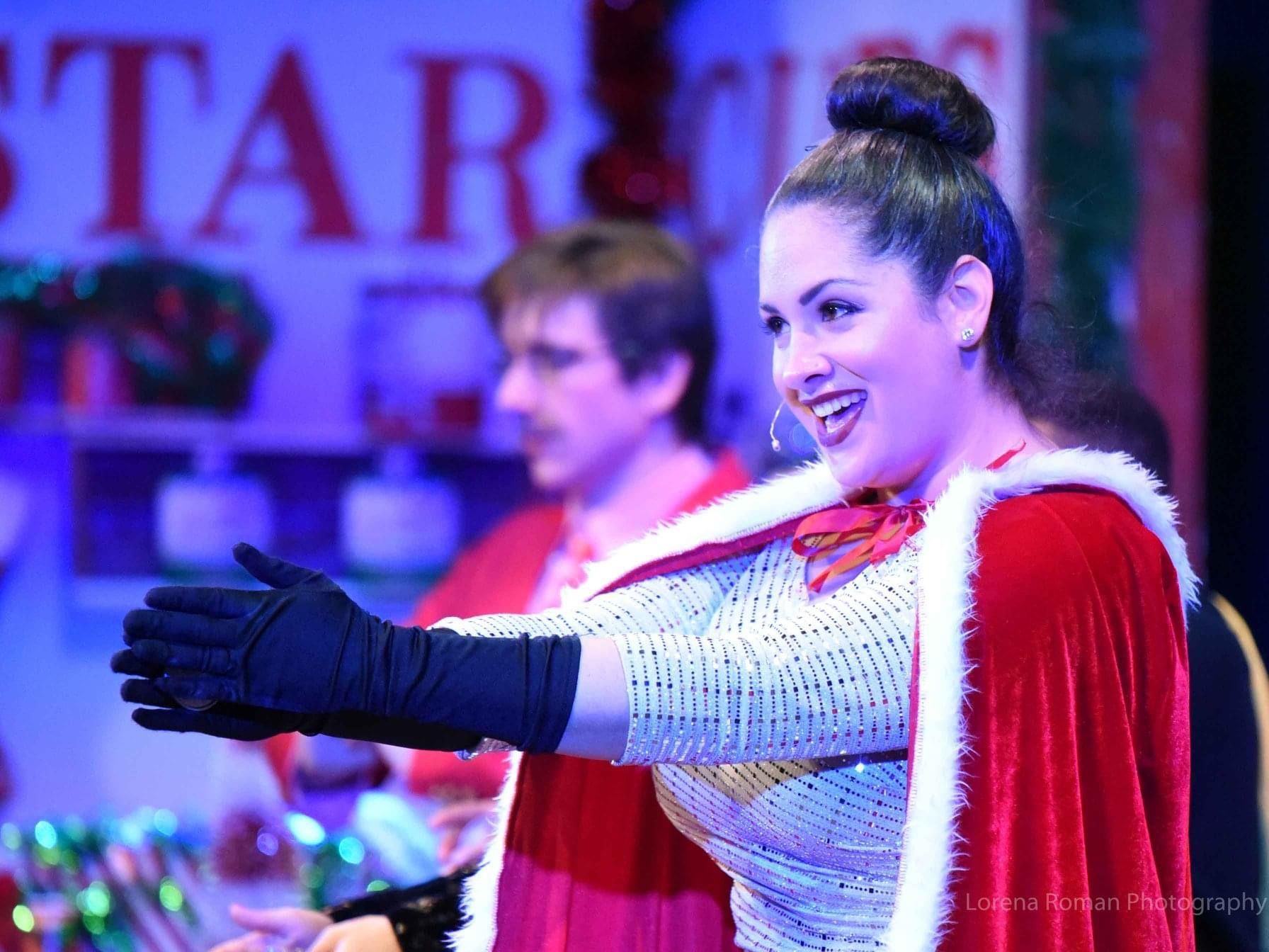A woman in a cape and gloves is standing in front of a sign that says star