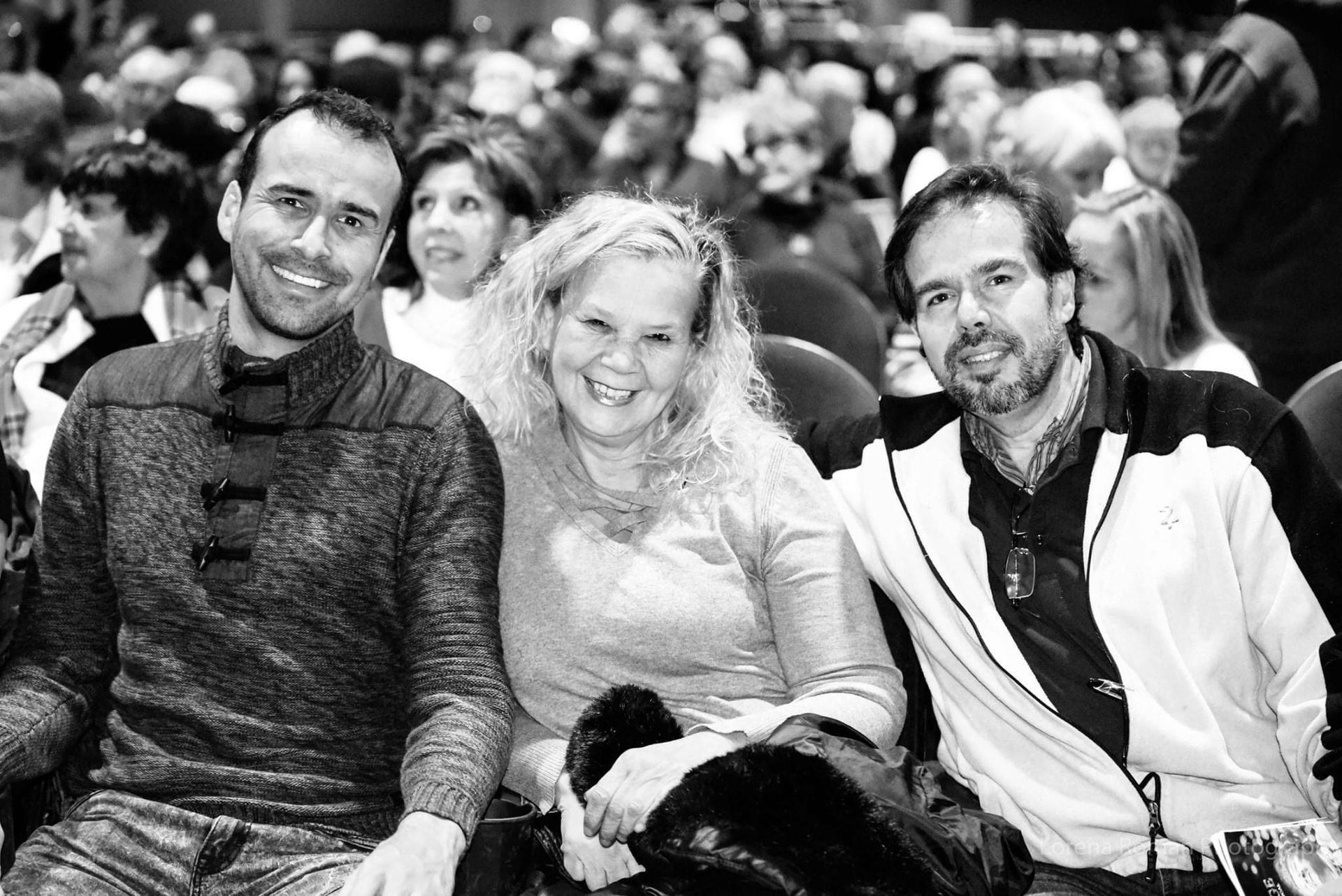 A black and white photo of three people sitting in a theater.