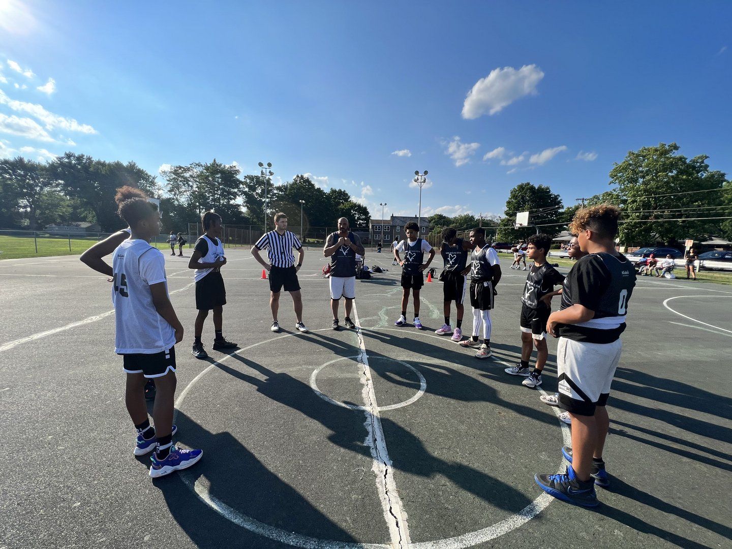 A group of people are standing in a circle on a basketball court.