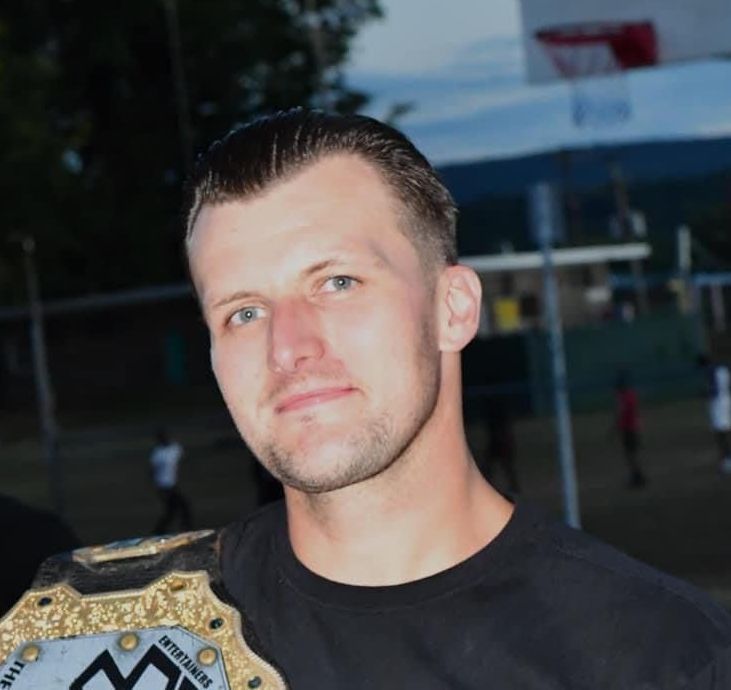 A man in a black shirt is holding a belt with the number 25 on it