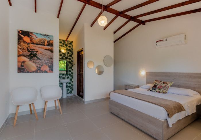 Un dormitorio con una cama, sillas y un cuadro en la pared.