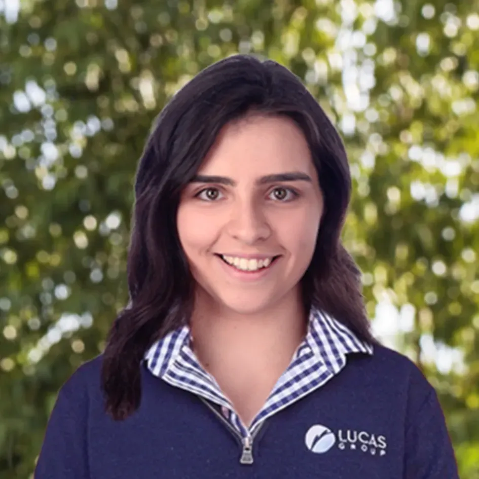Woman in navy shirt with striped collar smiles in front of blurry green background.