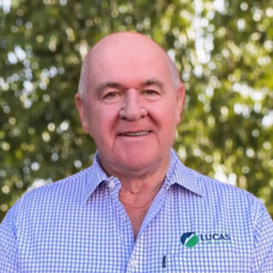 Bald man wearing a blue-and-white button-down shirt smiles; the Lucas logo is on the shirt pocket.