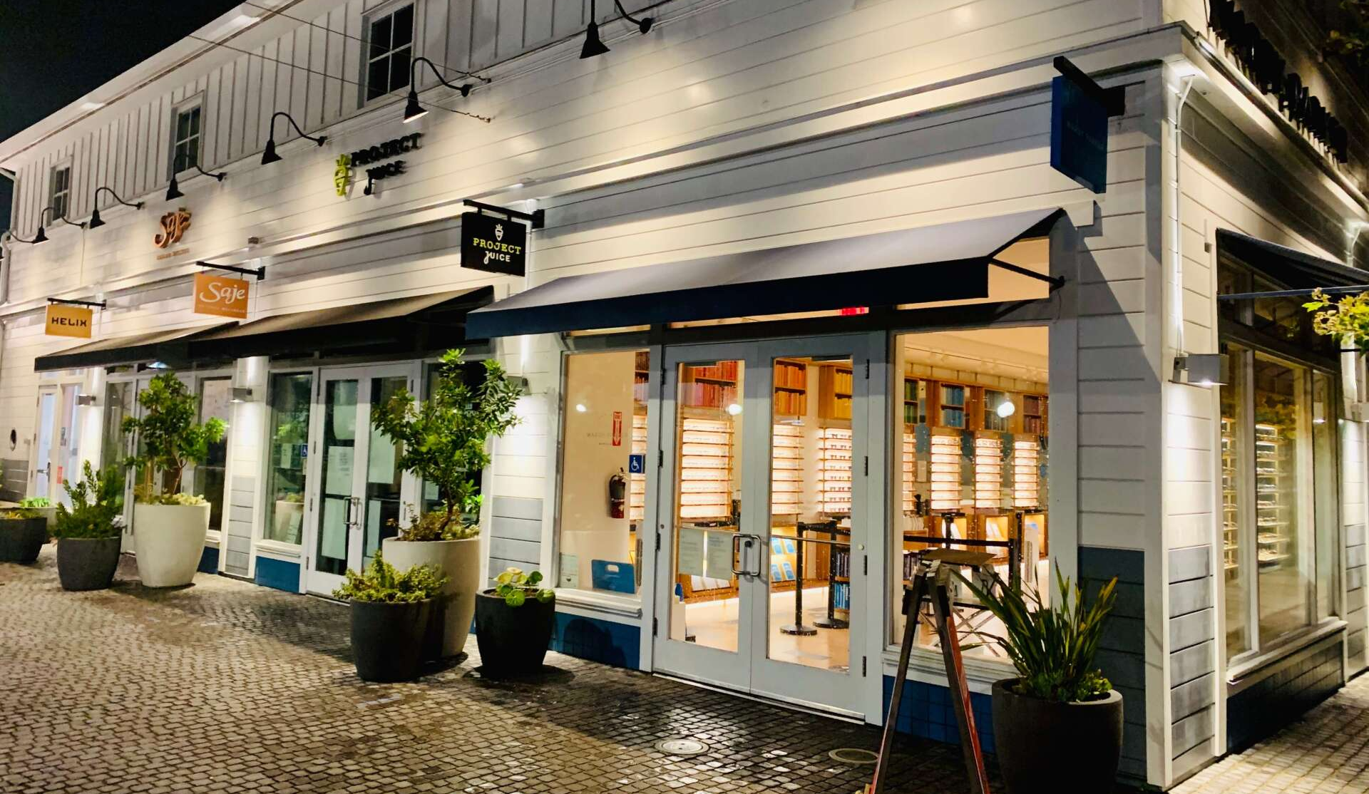 A white building with a blue awning is lit up at night.