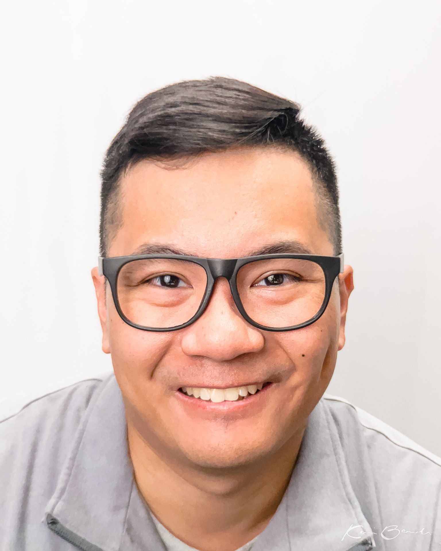 Headshot of graphic designer Kevin Baculi wearing glasses on white background