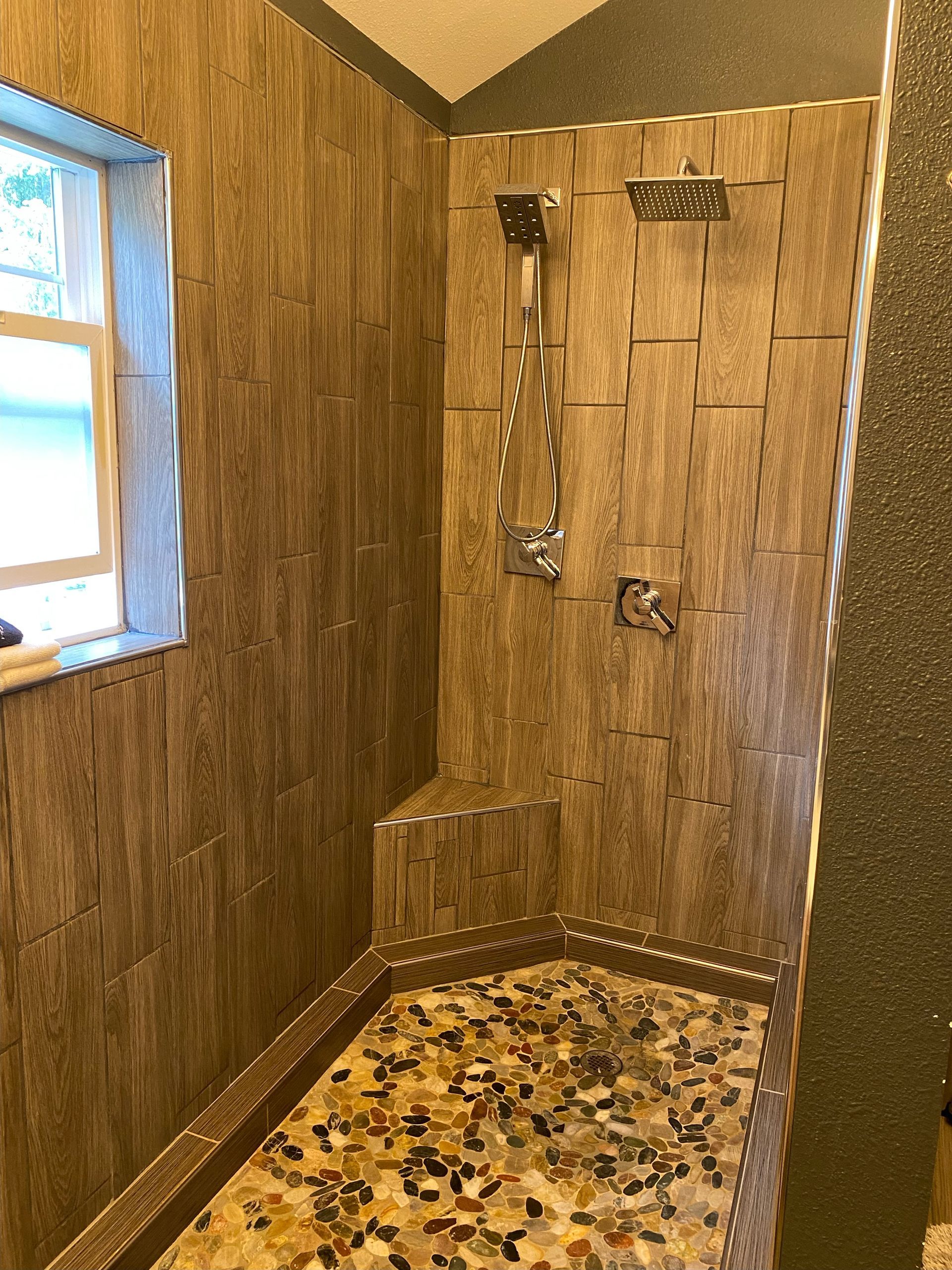 A bathroom with a walk in shower and a window.