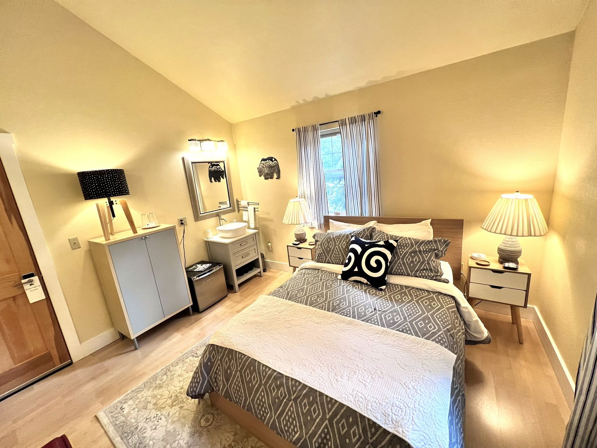 A bedroom with a bed , nightstands , lamps and a mirror.