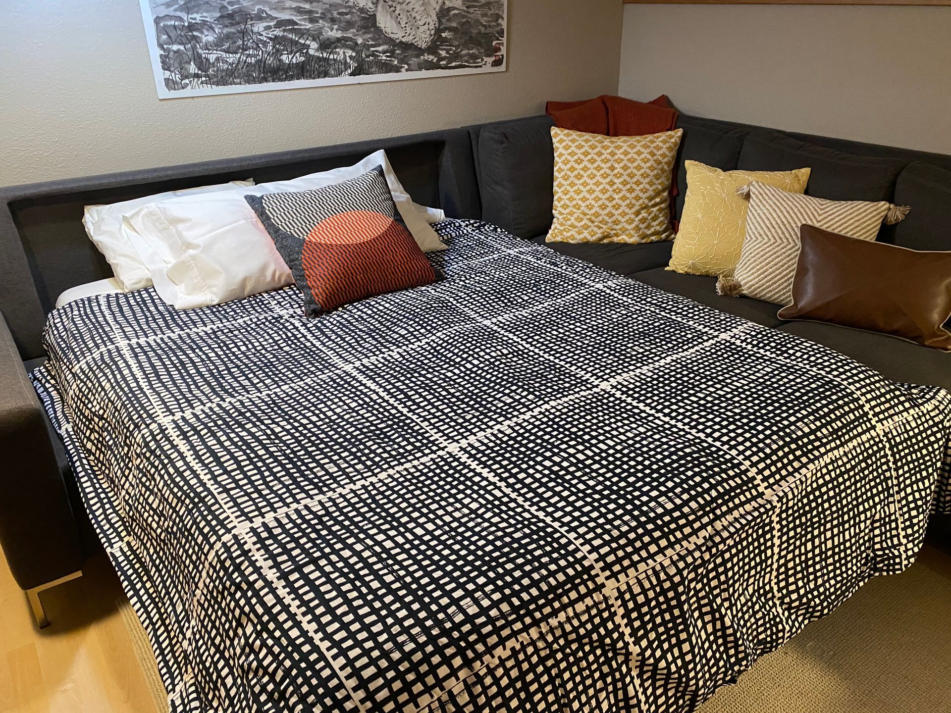 A bed is sitting next to a couch with pillows on it.