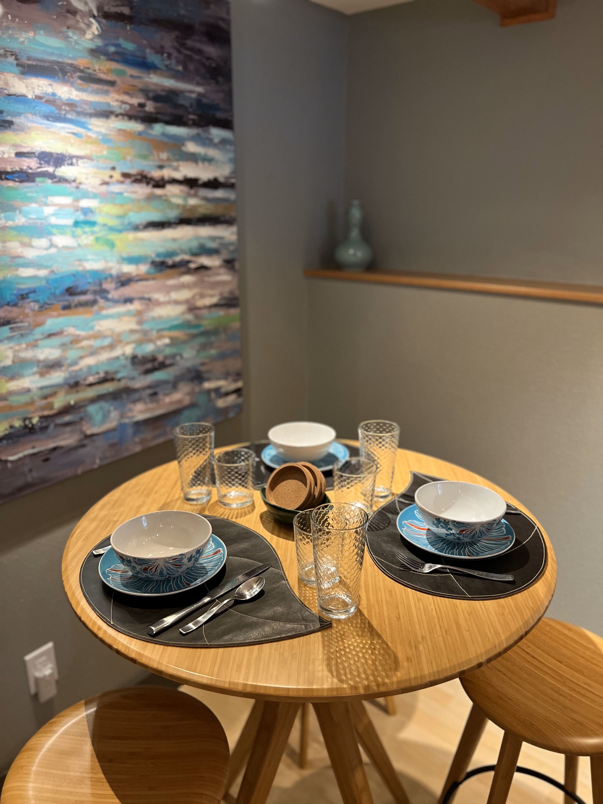 A table with plates and glasses on it in front of a painting