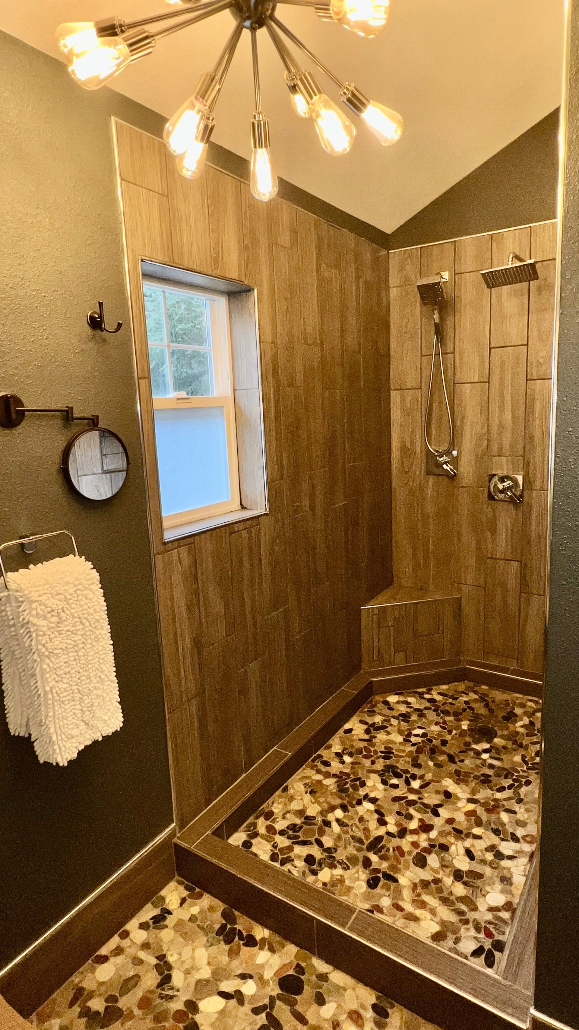 A bathroom with a walk in shower and a window.