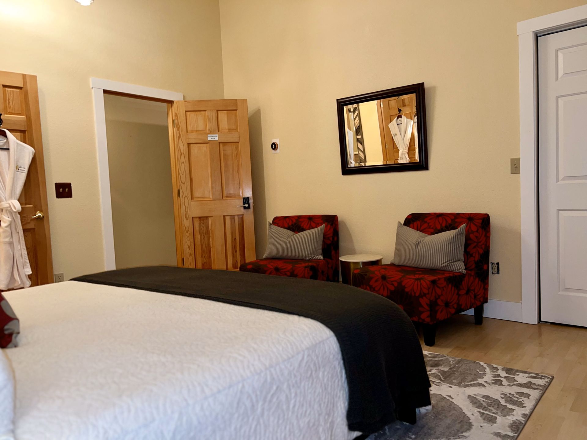 A bedroom with a bed , chairs and a mirror