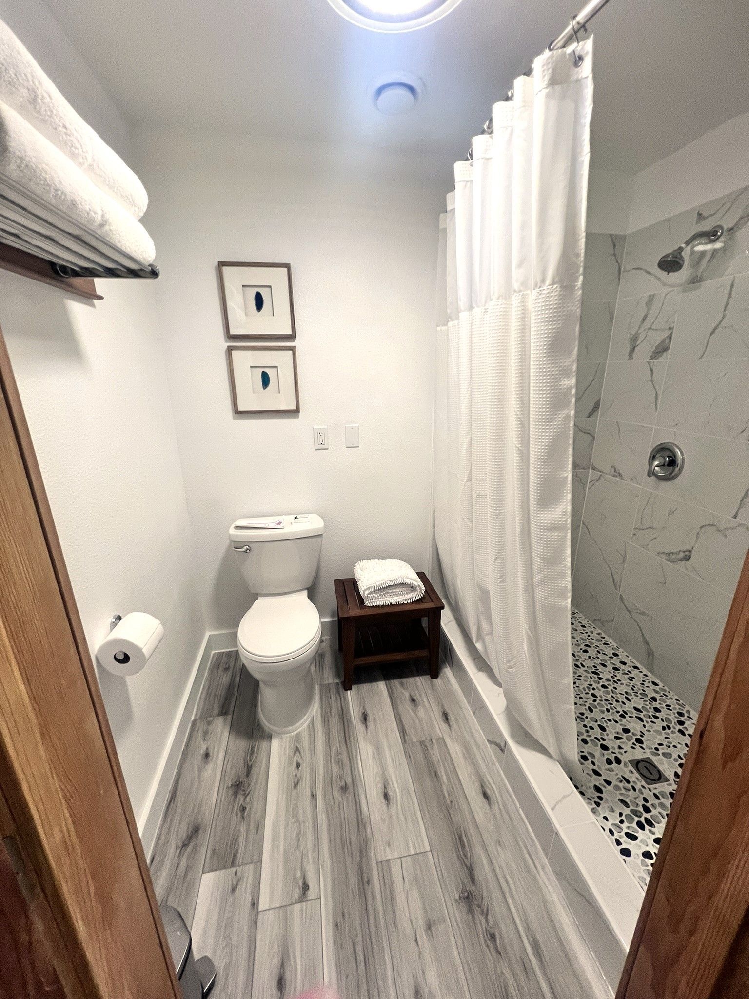 A bathroom with a toilet , shower , and towels.