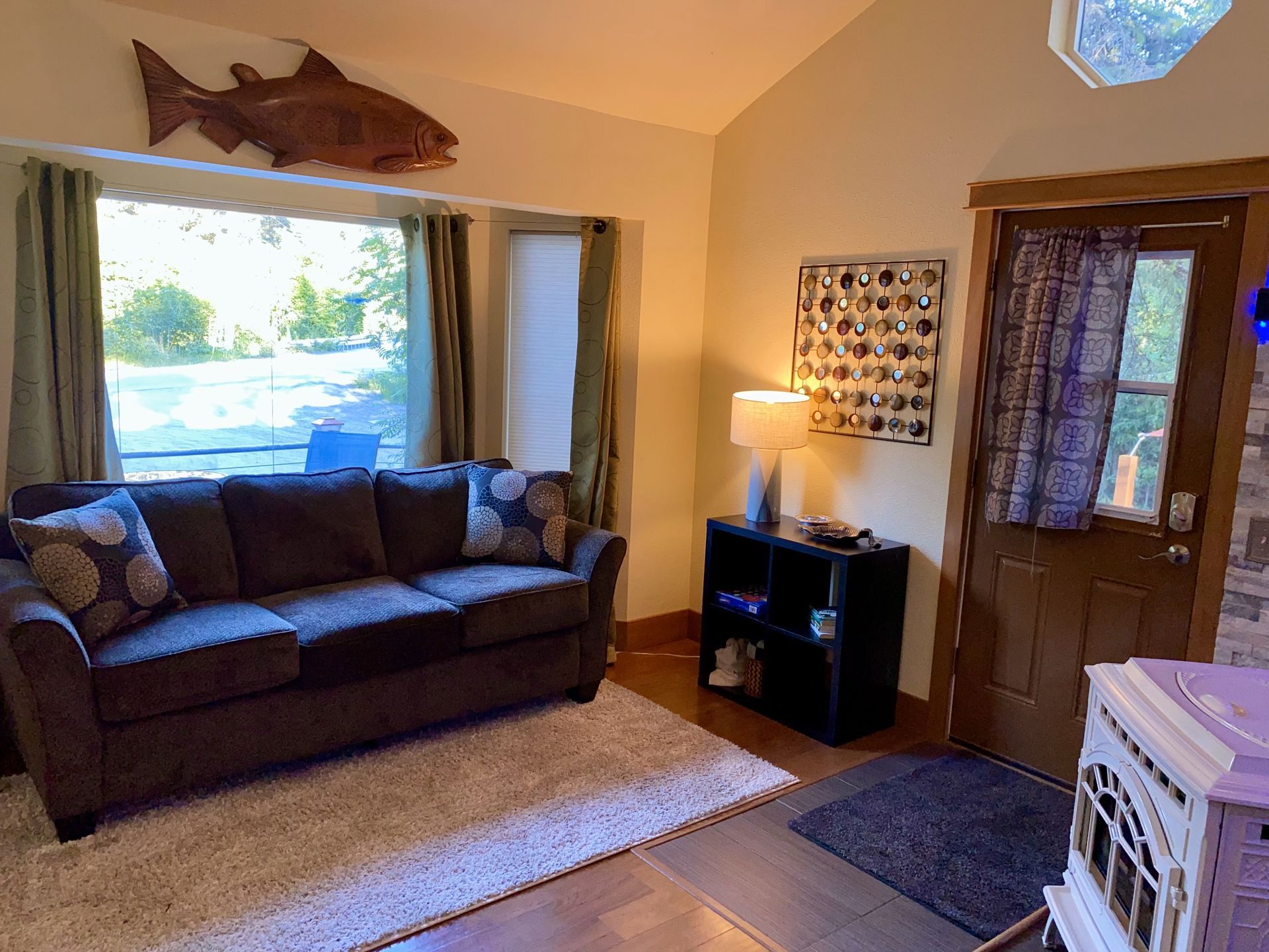 A living room with a couch and a fish on the wall.