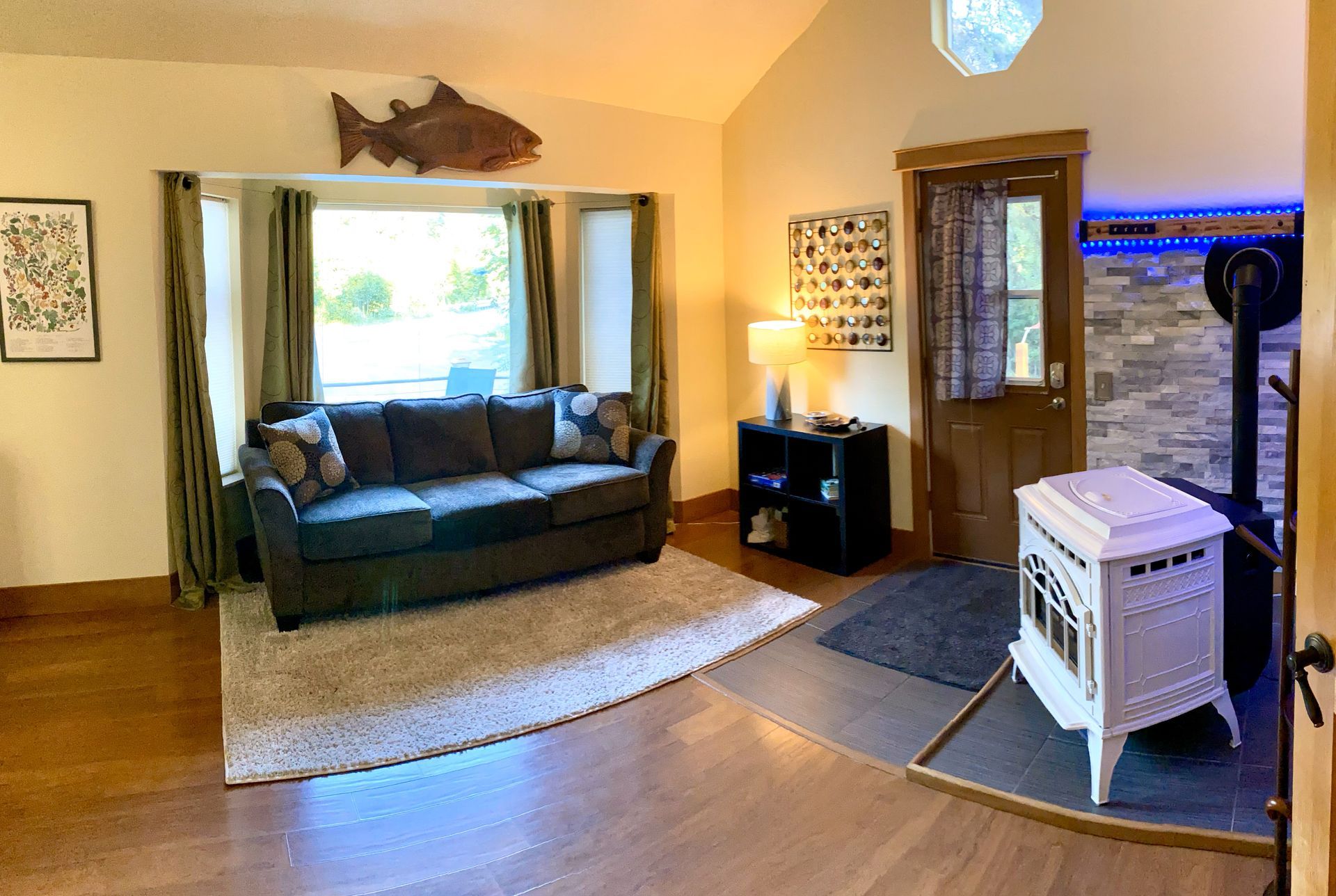 A living room with a couch , fireplace , and fish on the wall.