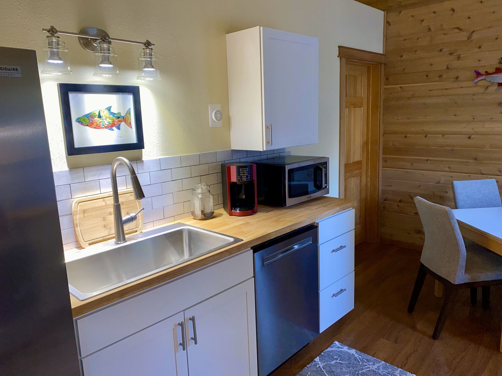 A kitchen with a sink , refrigerator , dishwasher and microwave.