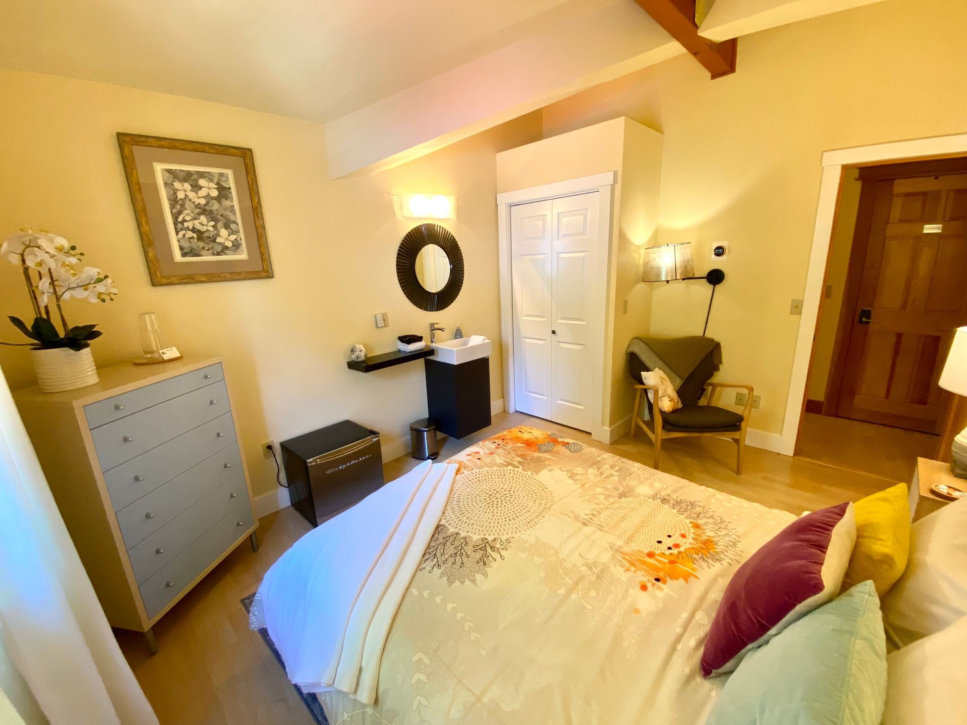 A bedroom with a bed , dresser , chair and mirror.