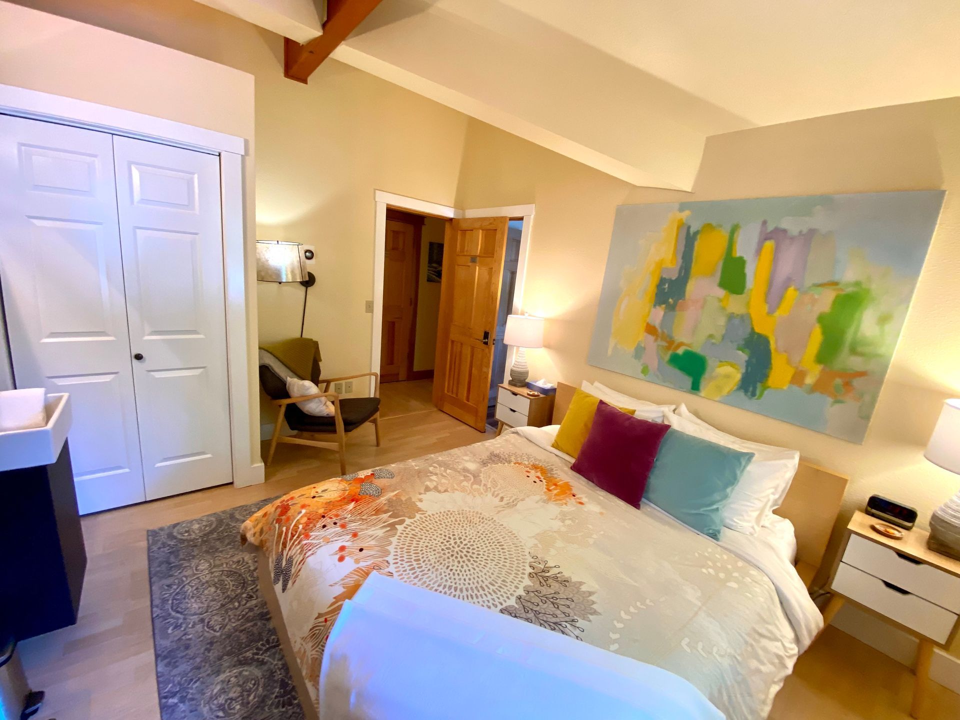 A bedroom with a large bed and a painting on the wall.