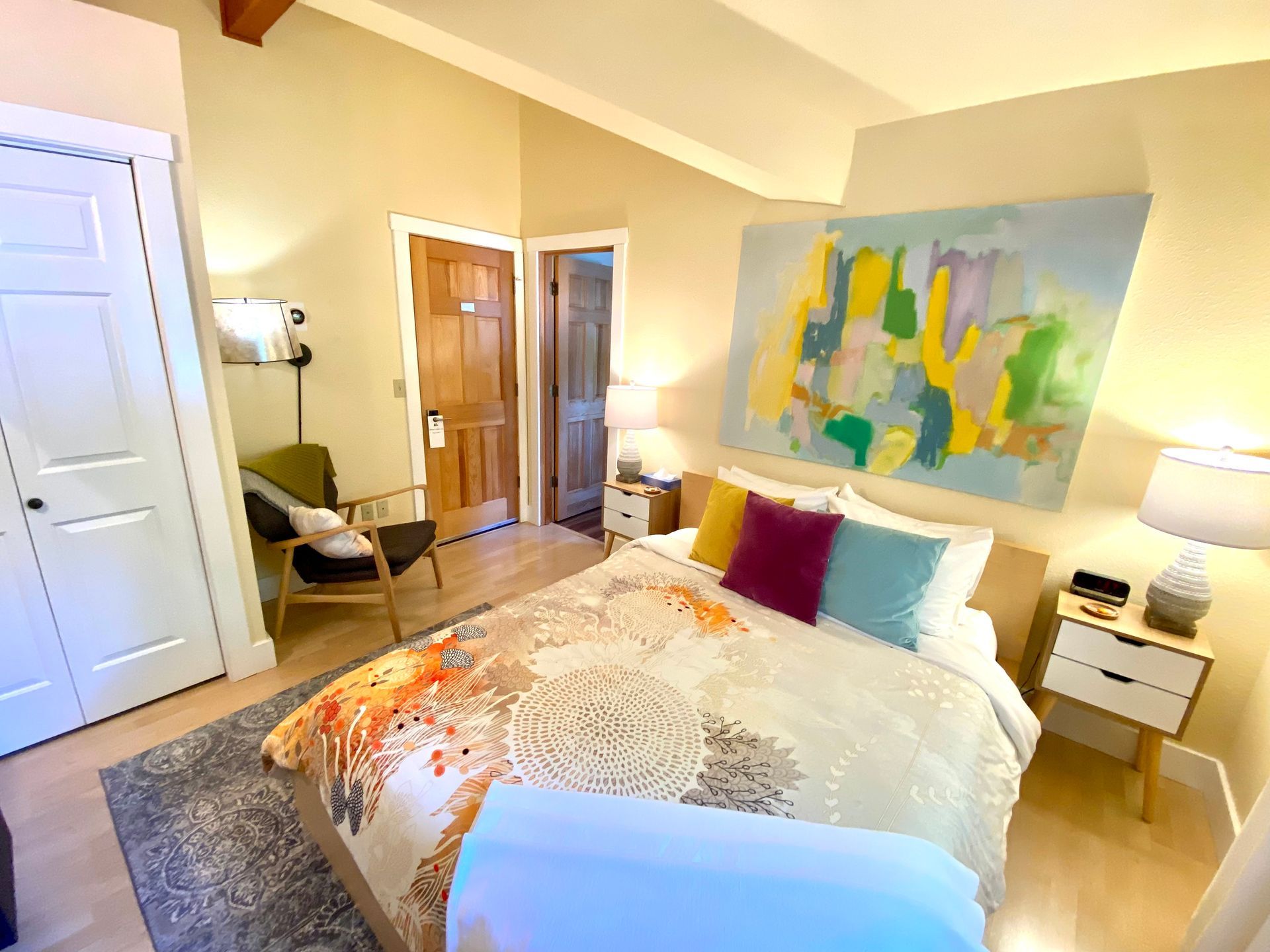 A bedroom with a large bed and a painting on the wall.