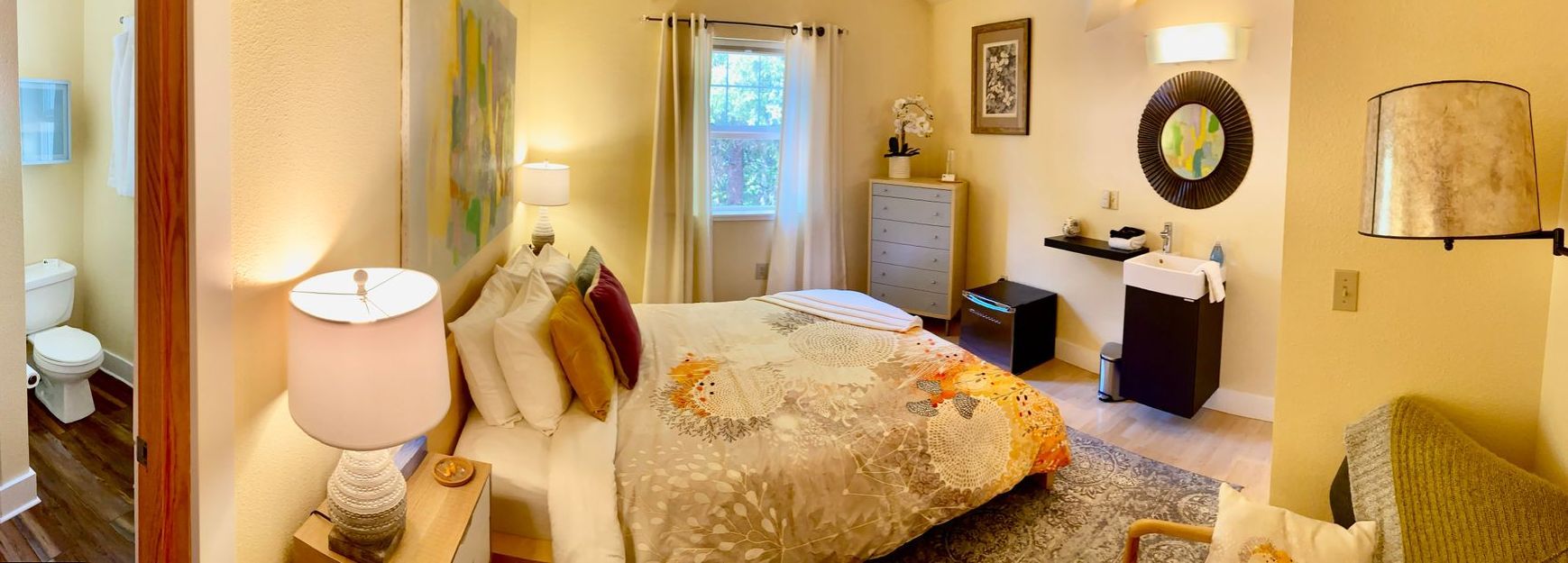 A bedroom with a large bed and a bathroom.