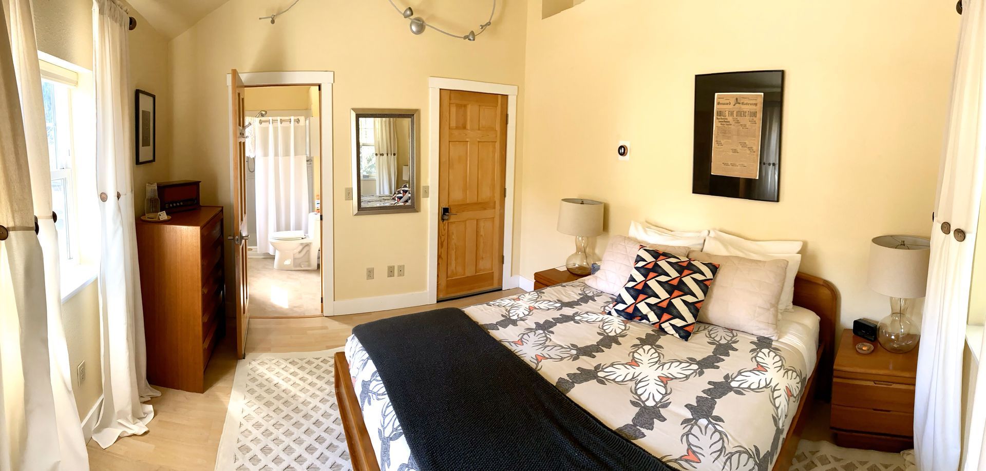 A bedroom with a bed , nightstand , mirror and dresser.