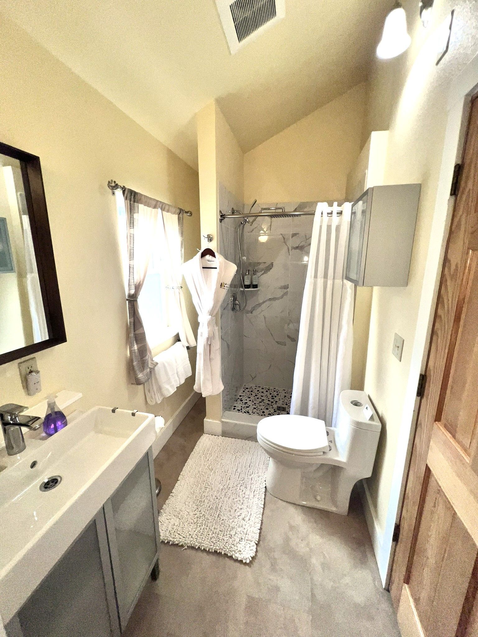 A bathroom with a toilet , sink , mirror and shower.