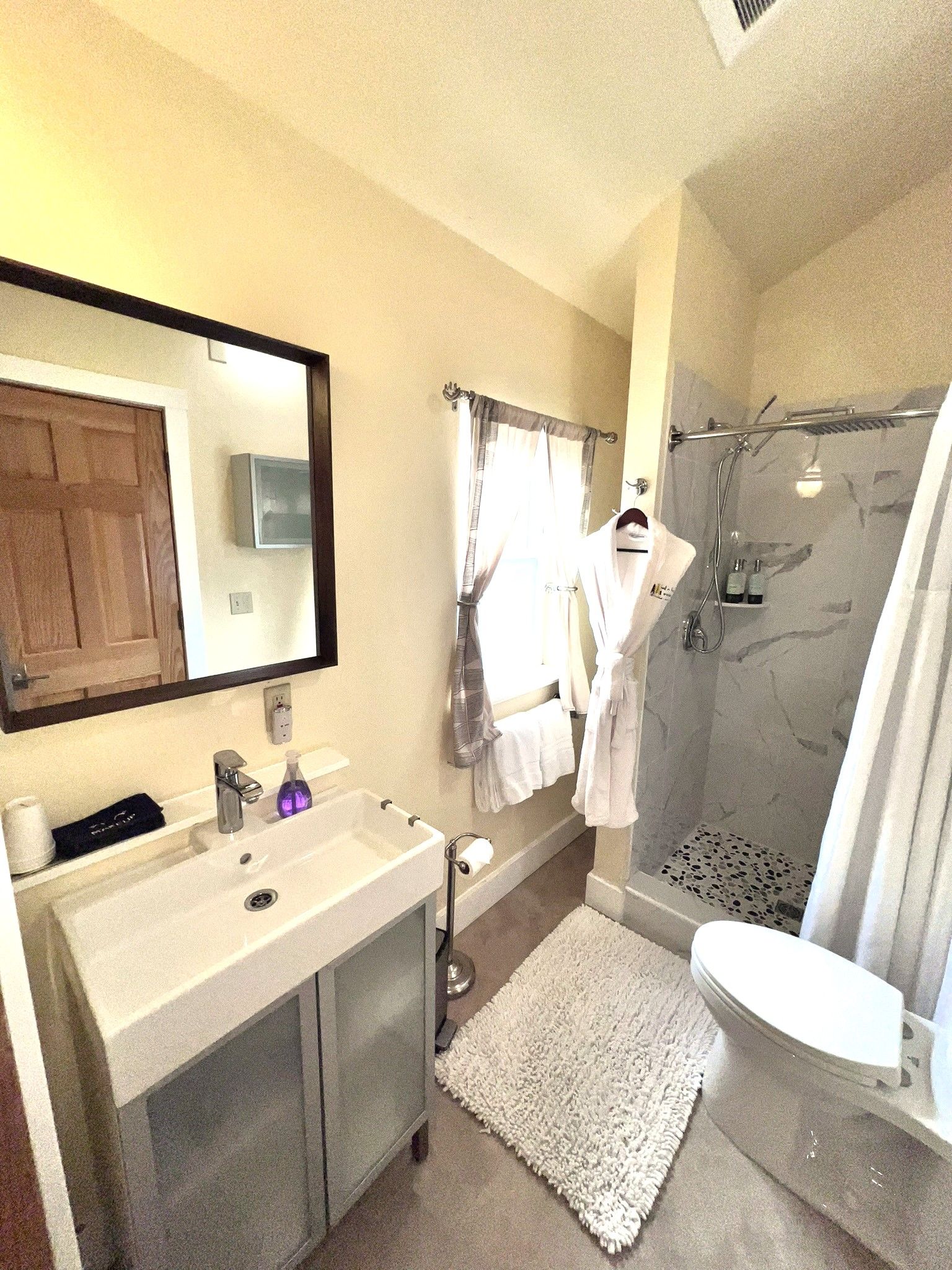 A bathroom with a sink , toilet , shower and mirror.