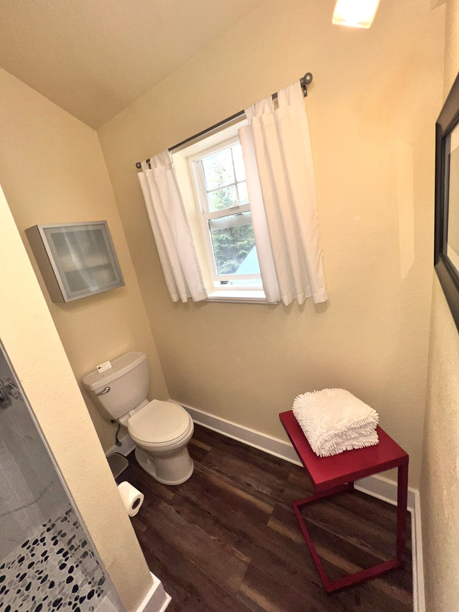 A bathroom with a toilet , towels , and a window.