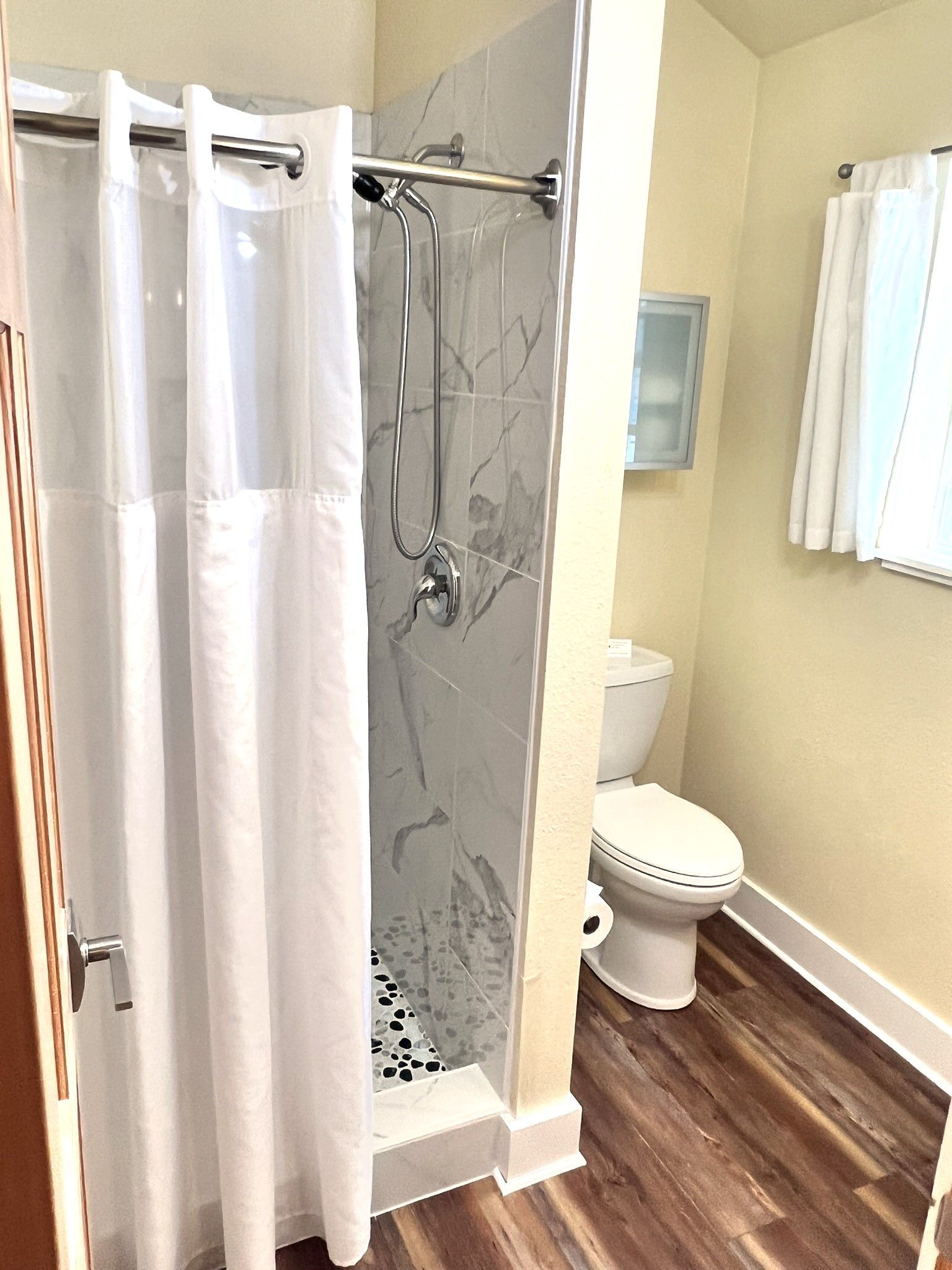 A bathroom with a shower , toilet , and mirror.