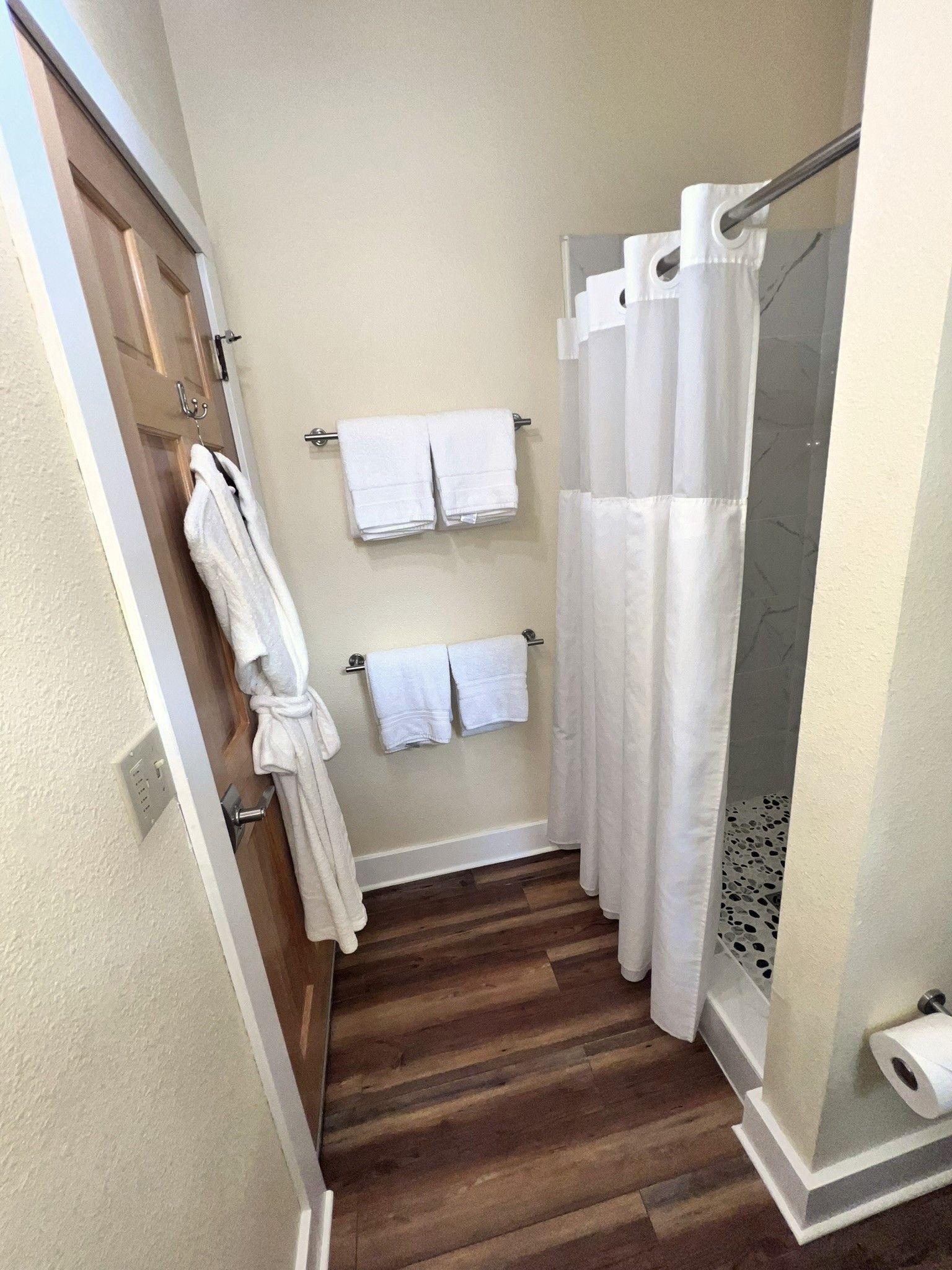 A bathroom with a shower curtain and towels on the wall.
