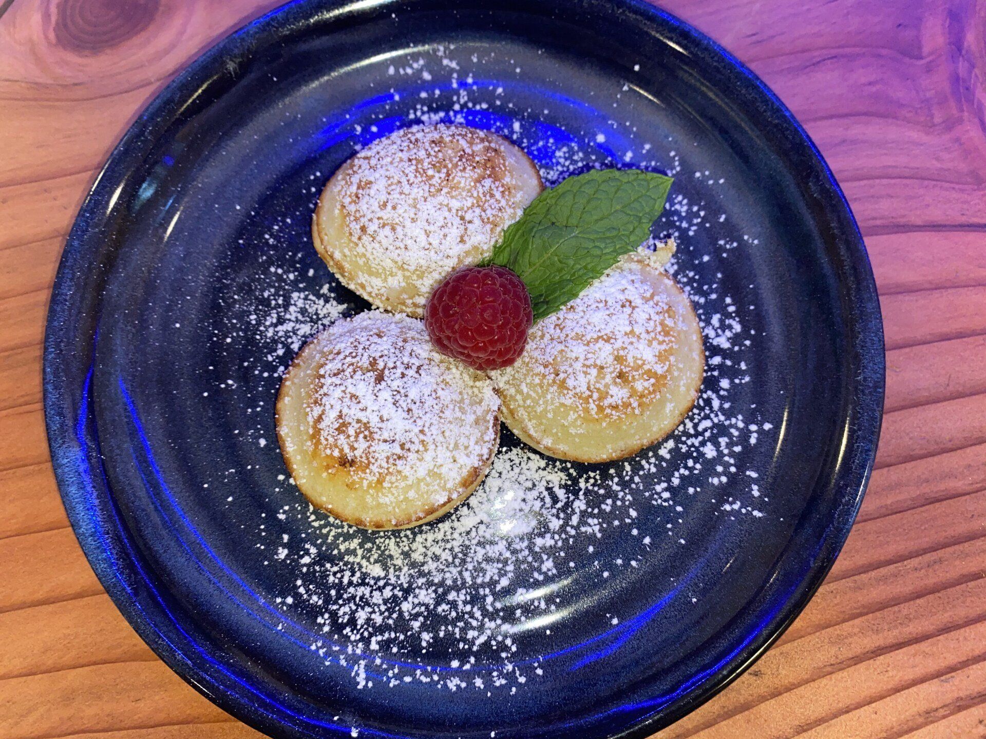 Bell In The Woods 3 course gourmet breakfast. A plate with 3 pancakes topped with powered sugar and garnished with a raspberry and a mint leave.