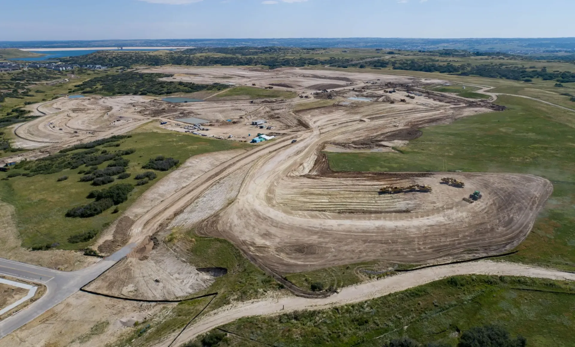 Aerial view of a vast construction site with earthmovers on dirt paths.