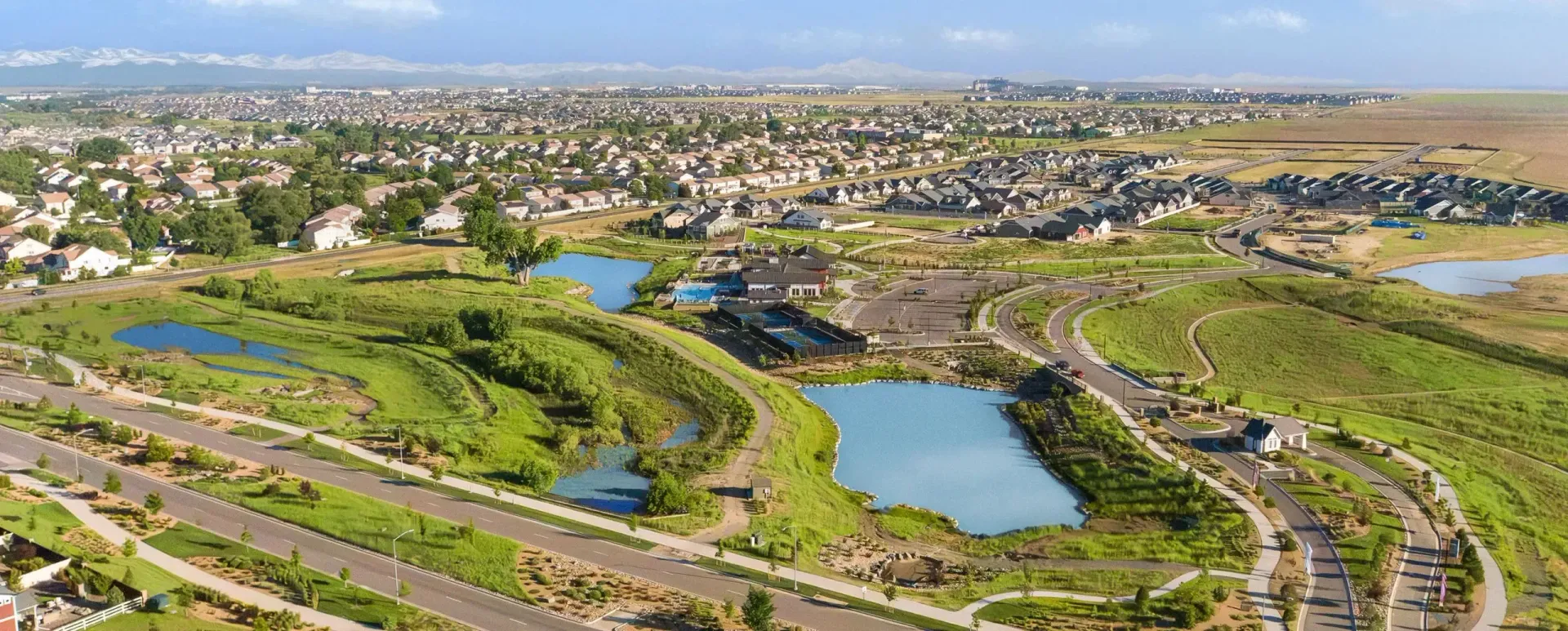 Aerial view of a suburban landscape with winding roads, and green fields.