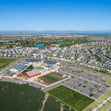 Aerial view of a suburban neighborhood with a large school complex, sports fields, and parking lot.