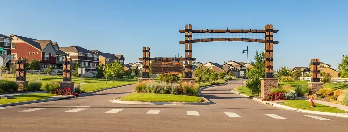 Wooden archway entrance to a suburban neighborhood with well-manicured lawns.