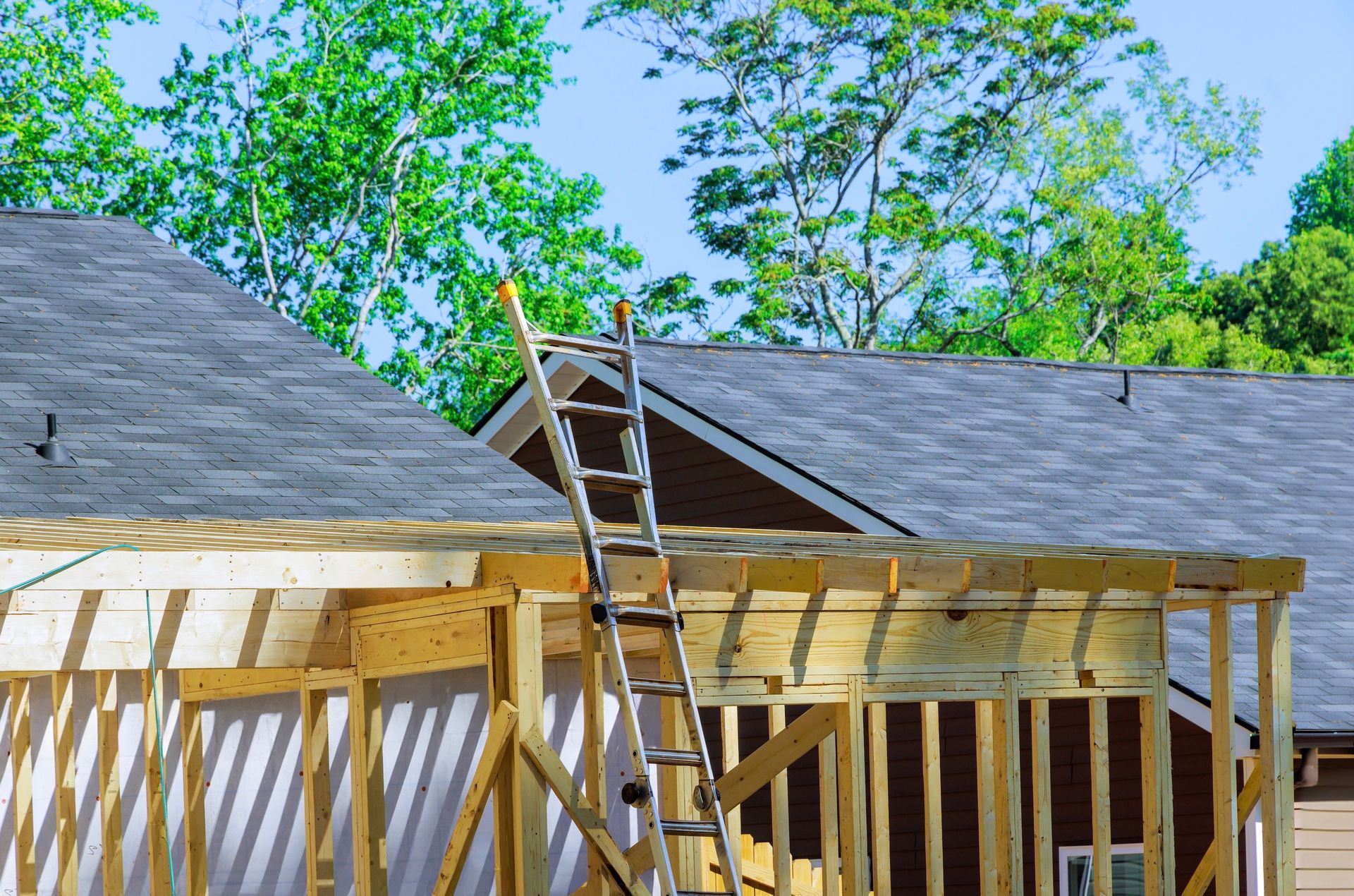 Construction site with a ladder leaning on a roof. Wooden framing is visible.
