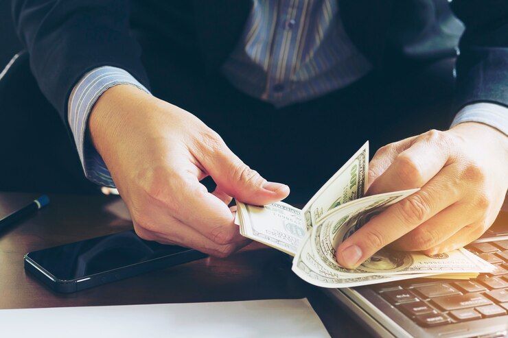 A Man Is Sitting At A Desk Counting Money - Professional Security in Darwin, NT