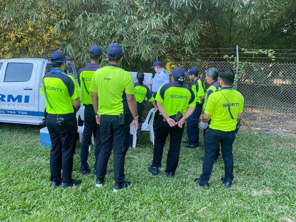 A Group Of Men In Neon Yellow Shirts Are Standing In A Grassy Field - Professional Security in Darwin, NT