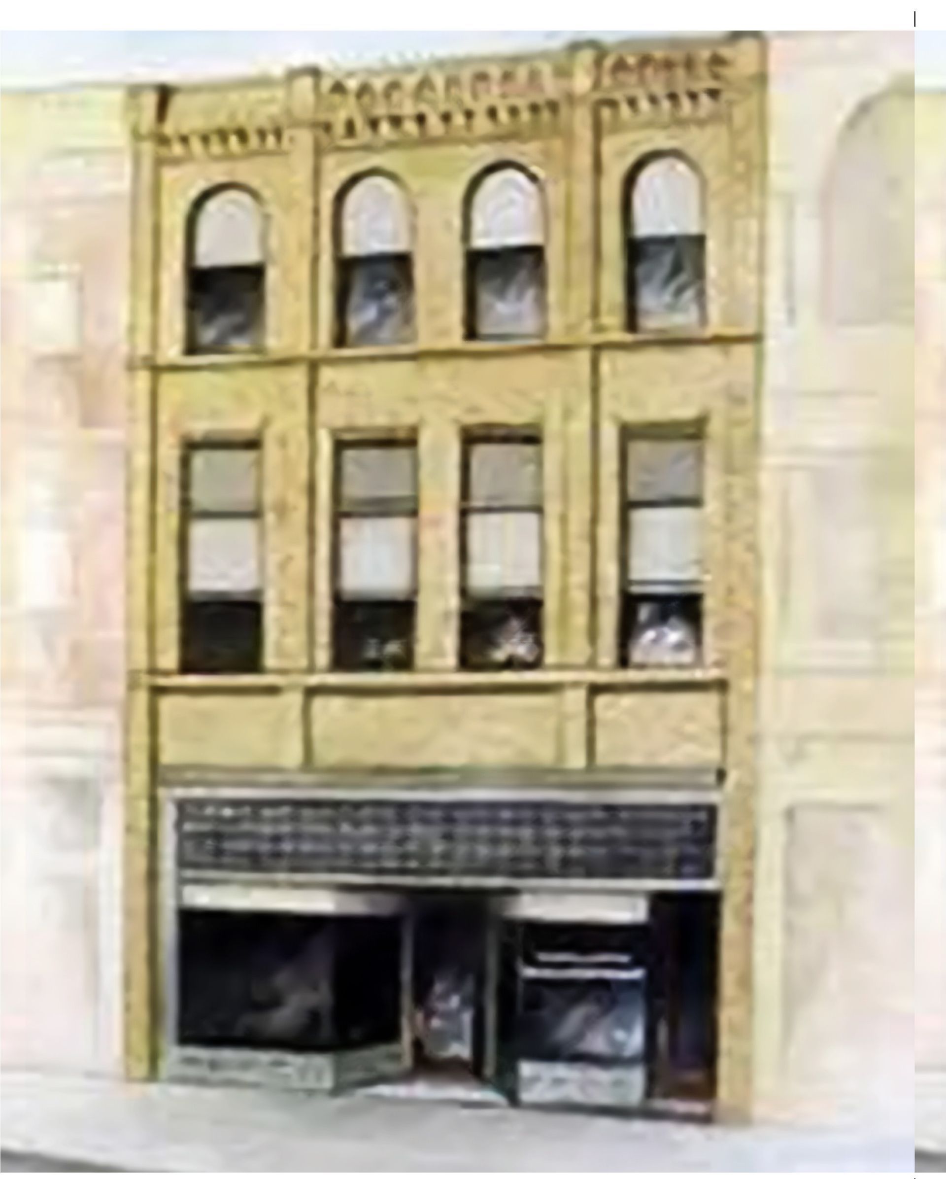 Old yellow brick storefront with arched upper windows and a dark ground-floor entrance