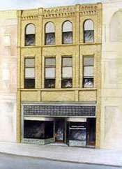 Old yellow brick storefront with arched upper windows and a dark ground-floor entrance
