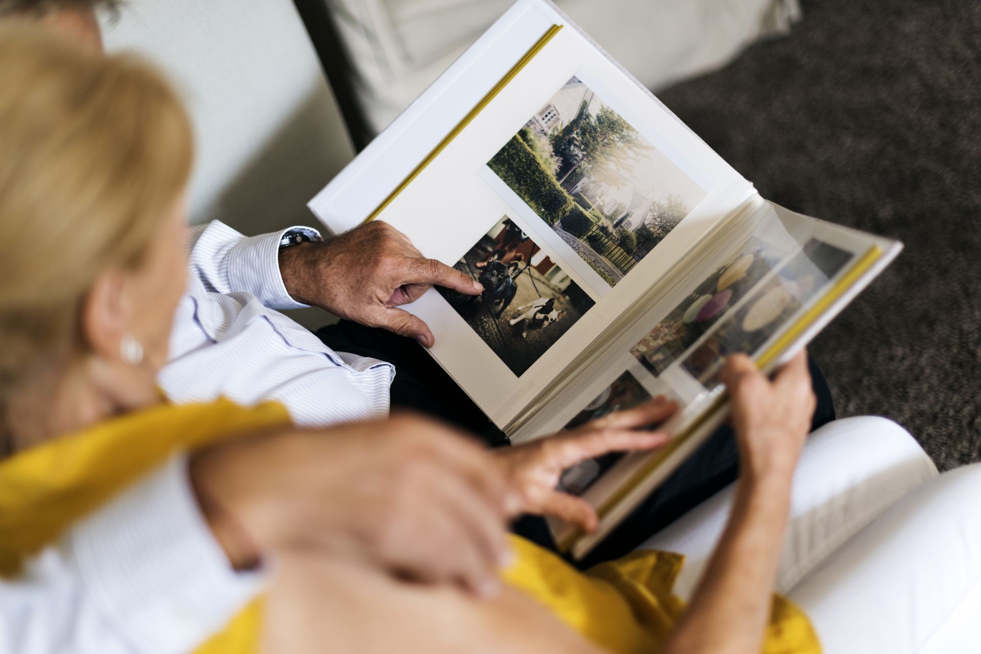 Two people on a white couch looking through a photo album with landscape pictures
