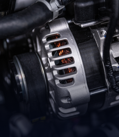 Close-up of a car engine alternator with silver housing and visible copper coils